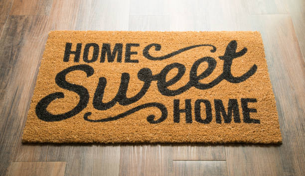 A doormat on a wooden floor with the text HOME Sweet HOME in a decorative font.