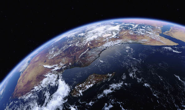 A view of Earth from space, showing a detailed portion of the continent with cloud formations. The landmass is bordered by a vast expanse of ocean, and the curvature of the planet is visible against the dark backdrop of space.