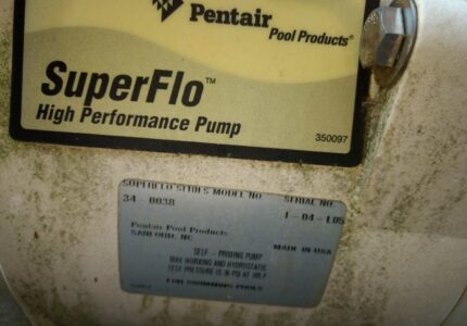 Close-up of a Pentair SuperFlo high performance pump label showing model number 34-0038. The label reads Pentair Pool Products, Self-Priming Pump, Made in USA, with specifications such as 155 PSI and 150°F. Some dirt is visible on the surface.