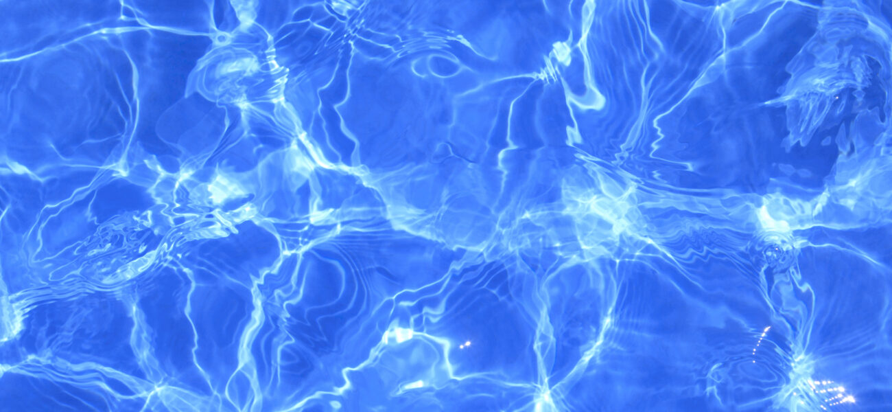 Clear blue water with sunlight creating ripples and reflections on the surface. Waves and patterns form abstract designs, showcasing the natural movement and play of light.